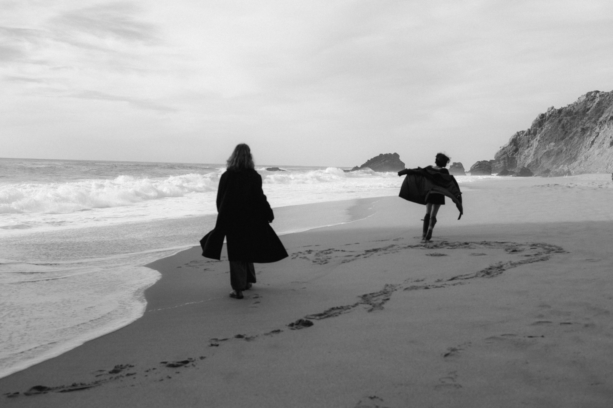 Couple running across a wild beach in black and white